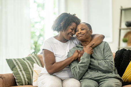 adult daughter hugging senior mother